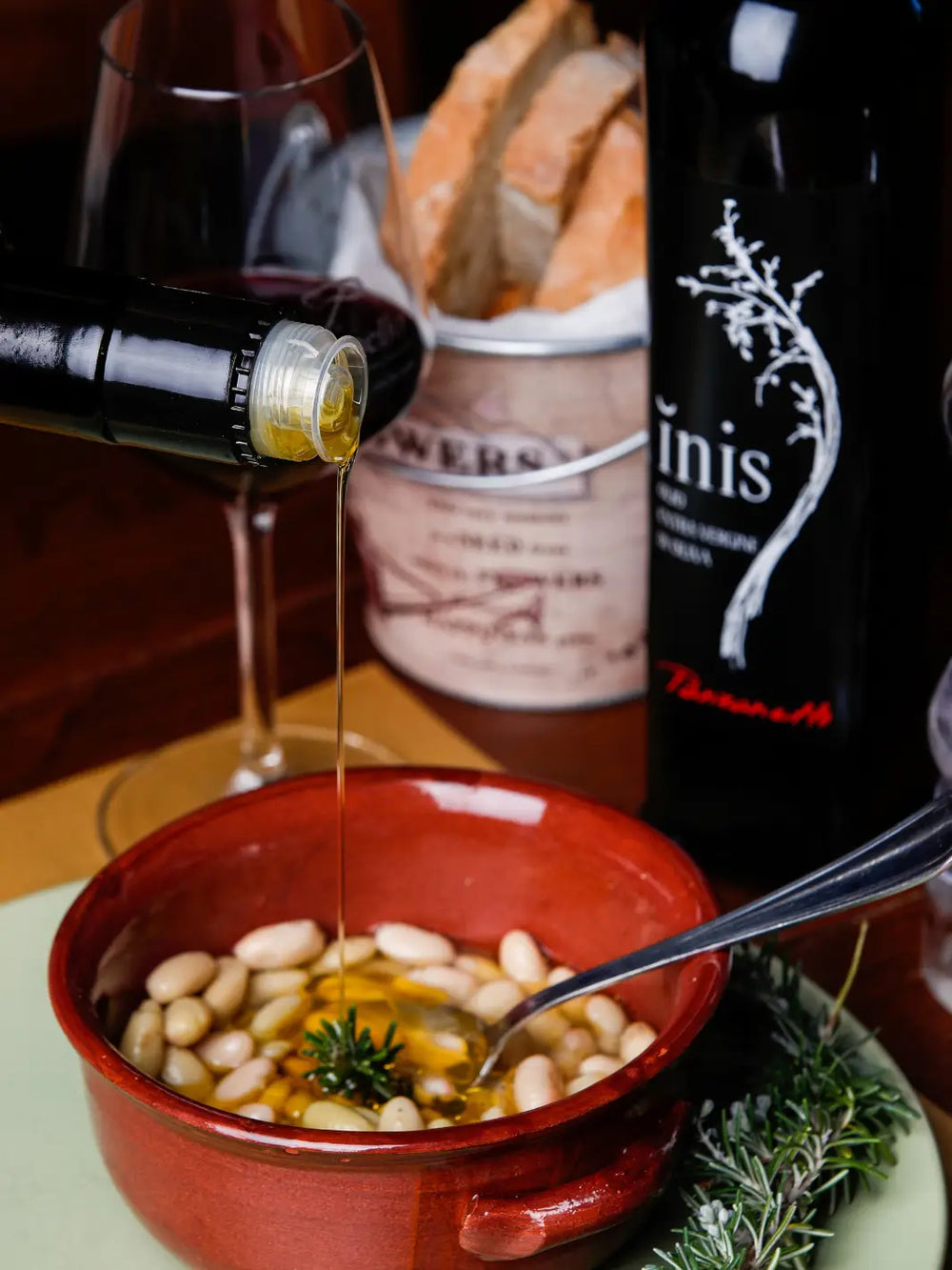 Olio Nuovo Inis Panzanello 2024 da 500ml colato dentro ciotola di ceramica con fagioli e rosmarino